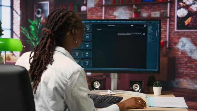 Woman seated at desk using AI LLM chatbot software in modern urban home office. Person requesting help from large language model program on computer in bright apartment workspace, camera B