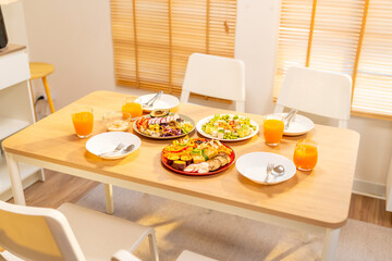 Vegetarian or vegan food vegetables salad with tofu on serving dish and orange juice on dining table in the kitchen. People cooking and having dinner eating healthy food from plant at home
