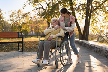 Caregiver with elderly woman in wheelchair at park