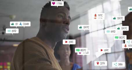 Image of social media notifications over african american colleagues discussing at casual office