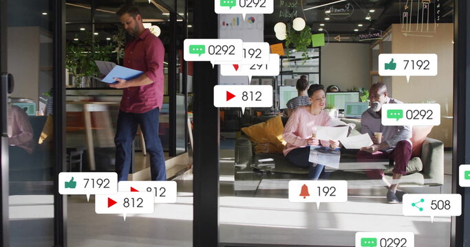 Image of social media notifications over diverse colleagues talking at casual office - Powered by Adobe