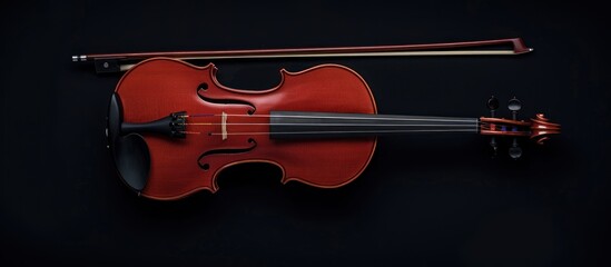 Fototapeta premium Red violin and bow on black background.