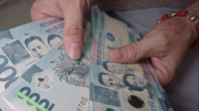 Hands Carefully Counting a Pile of 1000 Peso Bills