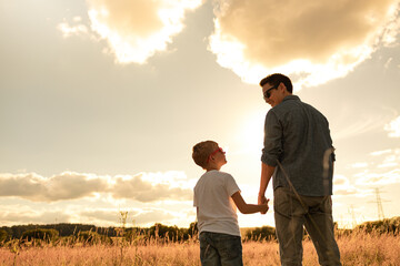parent and child father and son holding hands walking in nature park spending quality family time together
