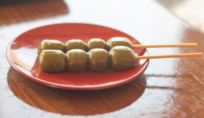 Close up of Japnaese sweet - green tea dango or rice dumpling skewers on a red plate. Kyoto, Japan