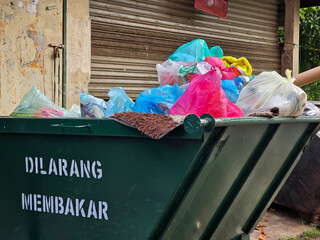 Large green metal dumpster filled with garbage.