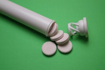 Effervescent Tablets with White Bottle on green Background Surface