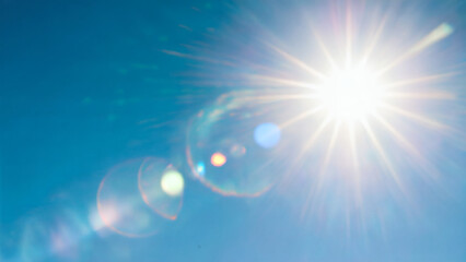 lens flare effects against a clear blue sky. The sun is visible in the top right corner, casting a bright glow and creating a lens flare effect