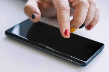 Close up of a man using mobile smart phone. arrow on the nail points to the smartphone screen. A man with a manicure taps on the smartphone screen.