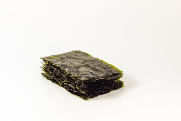 A flat lay composition featuring several sheets of dried nori seaweed arranged neatly on a pristine white background. The nori sheets exhibit a deep green hue and a slightly wrinkled texture.