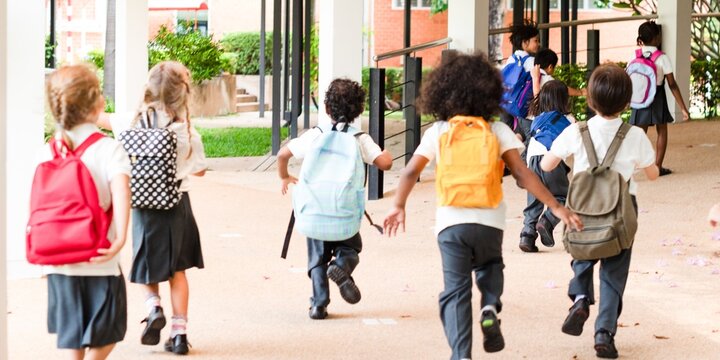 Children with backpacks running to school. Kids with backpacks, diverse group, excited for school. Backpacks and school uniforms on children. Cute little kids with backpacks in school.