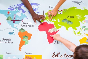 Children's hands exploring a colorful world map. Kids pointing at continents like Africa, Europe, and Asia. Educational map for children learning geography. Geography class in school with map.