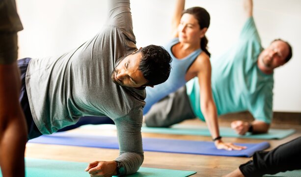 Diverse group of men and women practicing yoga. The yoga class includes various ethnicities, with participants sitting on yoga mats. Yoga for relaxation and fitness. Exercise and yoga for well being. - Powered by Adobe