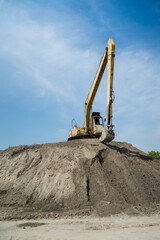 Excavator on earthmoving. Open-pit mining. Backhoe dig sand, ground in quarry. Heavy  equipment on excavation on construction site. Excavator on groundwork, foundation. It on the top of mound .