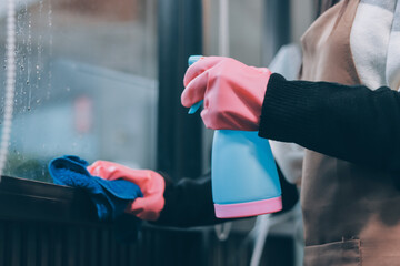 An employee of a professional cleaning service in overalls washes the glass of the windows of the...