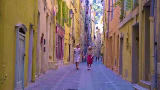 A couple Exploring the vibrant alleyways of Menton, France filled with colorful buildings and quaint charm. Laughter and joy fill the air as friends enjoy a lovely day together.