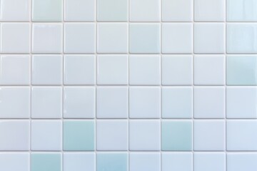 A clean, light-colored tiled wall featuring small square tiles arranged in a grid pattern, creating a subtle gradient effect.