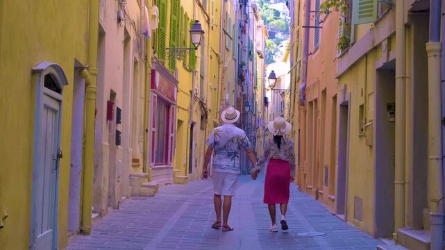 Couple enjoys a romantic walk through the vibrant, sun-kissed streets of Menton France. The quaint architecture and charming atmosphere create an enchanting backdrop for their adventure.