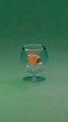 A still composition of a clear glass and heart-shaped red and white striped candies on a gradient green surface