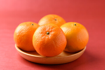Mandarin tangerine orange fruit on wooden plate with red background, Lucky food in Lunar New Year or Chinese New Year
