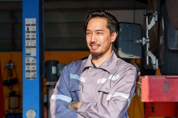 Mechanic standing confidently in garage with crossed arms, symbolizing professionalism, expertise, and trust in small business automotive repair and maintenance services.