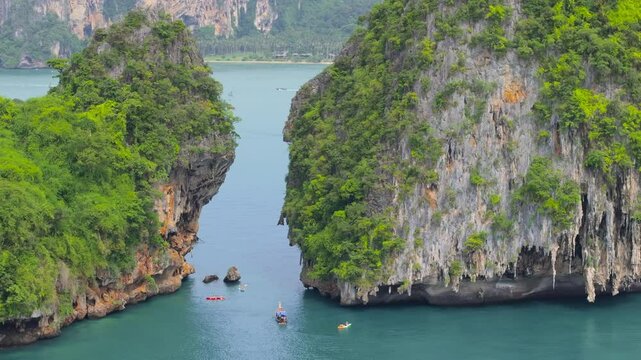 This stunning aerial photograph captures Krabi, Thailands lush greenery and iconic longtail boats gliding through serene blue waters, a paradise for nature lovers and explorers