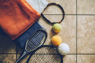 A creative flat lay of indoor sports gear: squash rackets, balls, and sports towels on a polished floor