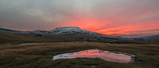 Fototapeta premium Dramatic Sunrise Mountain Landscape Pink Sky Snow capped Peak Reflection Puddle