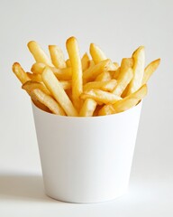 A close-up shot of French fries served in a small white paper cup, placed on a clean white background