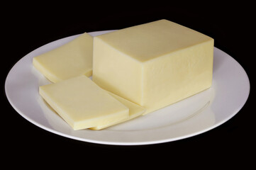 MOZZARELLA CHEESE BAR WITH SLICES ON DISH ISOLATED ON BLACK BACKGROUND