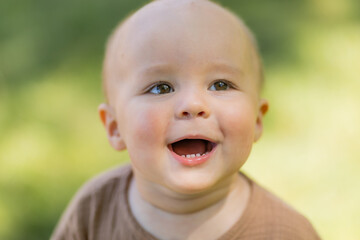Baby boy walks barefoot on the lawn in summer, children's muslin suit