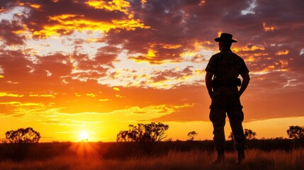 A sunset over the Australian outback with the silhouette of a soldier standing, representing the ANZAC spirit, emotional landscape photography with natural lighting 