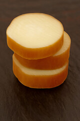 SMOKED PROVOLONE CHEESE IN PIECES ON THE DARK TABLE