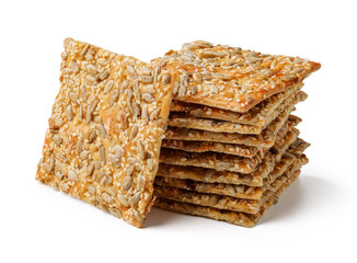 Crunchy oat and sesame crackers stacked in an artistic arrangement on a white background showcasing their texture and crispiness