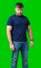 Fototapeta premium A man stands confidently on a bright green background wearing a dark t-shirt and jeans
