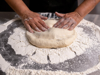 Woman making pizza dough on stainless steel counter
