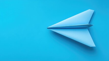 Naklejka premium A light blue paper airplane flying high against a bright blue sky, representing innovation, travel, or youthful energy