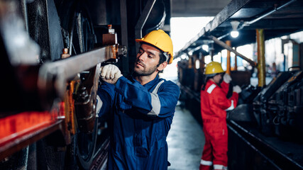 Male engineer worker maintenance locomotive engine wearing safety uniform, helmet and gloves in locomotive repair garage. Maintenance cycle concept.