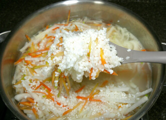 Cook healthy rice with vegetables. Stir rice with a spatula.

