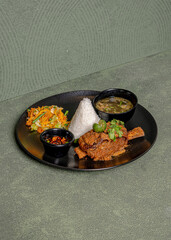 Grilled Ribs Served With Rice, Salad, A Bowl Of Soup, And Sweet Soy Sambal On A Black Plate, A Flavorful, Tasty, And Satisfying Meal.