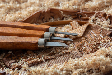 Carved ornate handmade wooden plaque with precision wood chisels on a sawdust chippings background