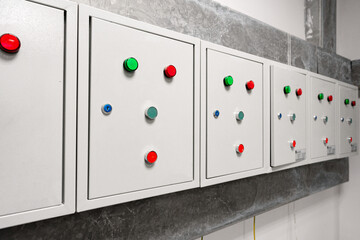 Control panels with colored buttons mounted on a grey wall in a modern facility setting during daylight