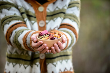 Woman hands holding bowl filled with ecological dried fruits and berries