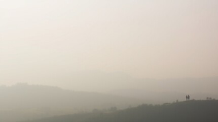 A serene landscape with a misty lake reflecting the trees and sky during a peaceful morning, surrounded by a foggy forest and a soft sunrise or sunset glow, evoking tranquility in nature