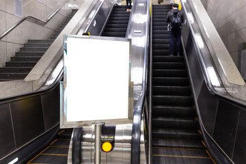 Blank advertising billboard with white in public, Empty white screen panel at Entrance Stairs Escalator, Sign board for advertisement. Frame wall media display public, mock up clipping path.