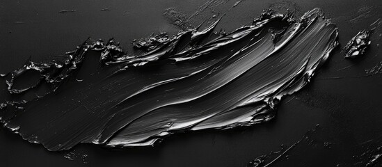 Black textured paint on a smooth surface showcasing deep glossy black tones with dynamic brush strokes creating an elegant dark background