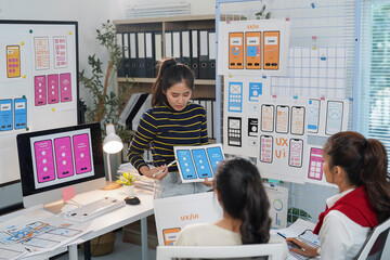Team of asian female web designers collaborating and discussing ux/ui design for a new mobile...