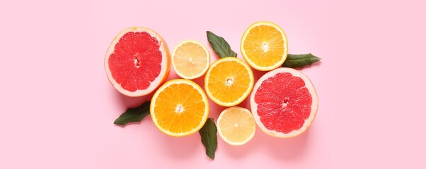 Many different cut citrus fruits on pink background, top view