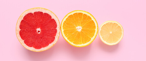 Slices of different citrus fruits on pink background, top view