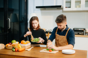 Discover a joyful couple preparing fresh vegetables, embracing healthy eating and teamwork in a...